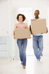Fototapeta na wymiar Couple with boxes moving into new home smiling