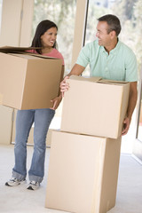 Couple with boxes moving into new home smiling