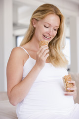 Pregnant woman eating bread and smiling