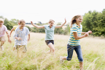 Five young friends running in a field smiling