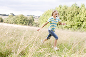 Young girl running in a field smiling