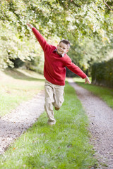 Young boy running on a path outdoors smiling