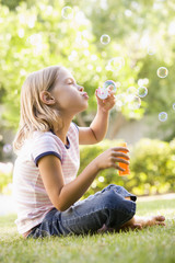 Young girl blowing bubbles outdoors