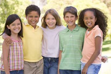 Five young friends standing outdoors smiling - Powered by Adobe