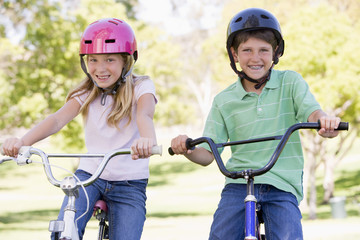 Fototapeta na wymiar Brother and sister outdoors on bicycles smiling