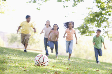 Obraz na płótnie Canvas Five young friends playing soccer