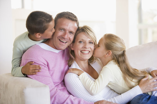 Family sitting in living room kissing and smiling