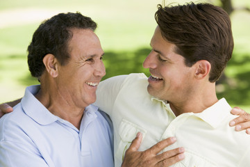 Two men standing outdoors bonding and smiling