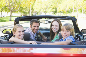 Family in convertible car smiling