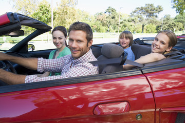 Family in convertible car smiling