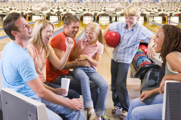 Family in bowling alley with two friends cheering and smiling