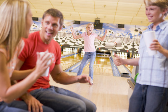 Family in bowling alley cheering and smiling