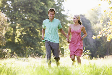 Fototapeta premium Couple running outdoors holding hands and smiling