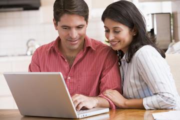 Couple in kitchen with laptop smiling