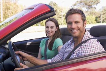 Couple in convertible car smiling - obrazy, fototapety, plakaty