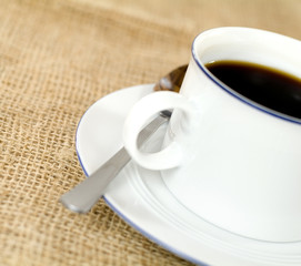 half-shown cup of fresh coffee on burlap