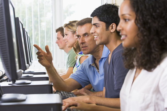 Teacher Assisting College Student In A Computer Lab