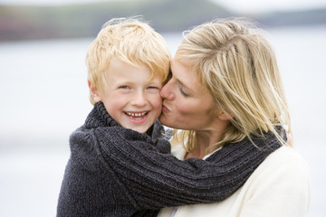 Mother kissing son at beach smiling