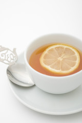 Tea serving in white cup with spoon and lemon slice