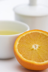 Tea serving in white cup with spoon, orange and lime slice in fr