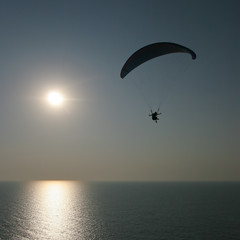 paraglider on sunset flying over the sea