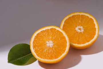 Two orange slices with leaf on white background with shadow