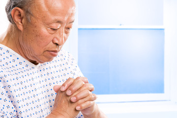 Praying senior asian in hospital