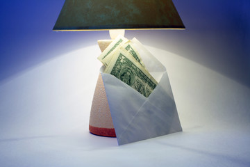 Envelope with money standing near electric lamp