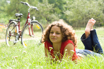 beautiful girl with a bicycle rests on a grass