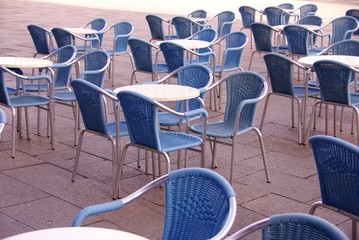 A te4rrace with blue chairs and round tables