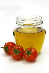 olive oil inside transparent jar and cherry tomato