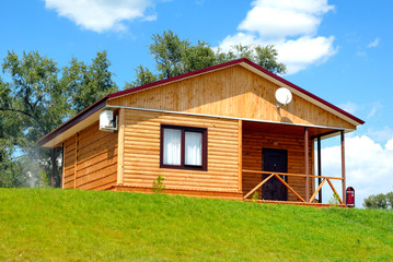 Obraz premium The wooden house with a lawn on a background of the blue sky