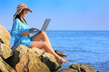 girl using a laptop near the sea