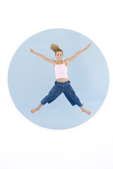 Young girl jumping with arms out smiling