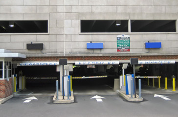 Parking garage entrance with signs and automatic gates.