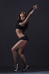 cute young female in lingerie posing on a dark background