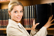 Portrait of business lady touching books that stand on shelf