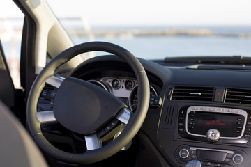 Wheel and dashboard of a car with sea background