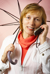 Middle years woman under the umbrella  speaks mobile phone
