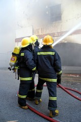 Firemen fighting a fire in a burning building with a water hose
