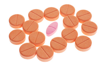 Red pill among orange favored lozenges on white background