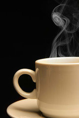 Cup of coffee close-up with steam over black background