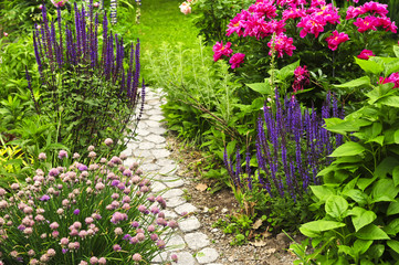 Naklejka premium Luksusowy kwitnący ogród letni z utwardzoną ścieżką