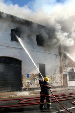 Fireman fighting a fire in a burning building with a water hose