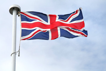 British flag on a mast, cloudy sky in background