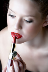 Beautiful blond woman with red lips applying lipstick