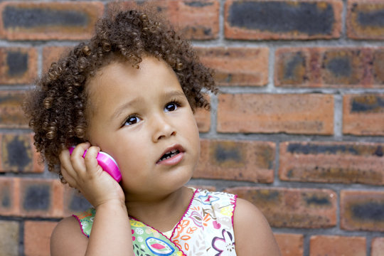 Young black baby girl talking on a toy cell phone
