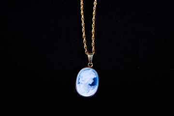 A traditional cameo on gold chain on black background