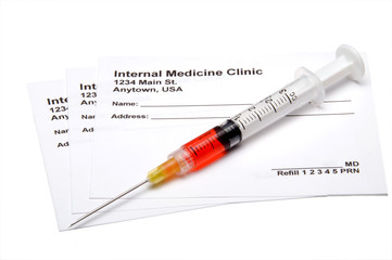 A medical prescription pad and a hypodermic syringe.