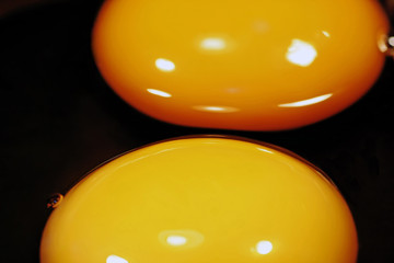 Two orange egg yolks isolated on black.